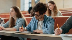 hispanic young man among his fellow students in the classroom. young bright people listening to a lecture and take notes while studying at the university.