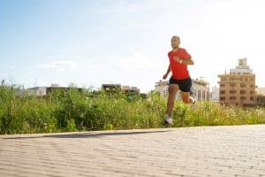 caucasian man running in the park. he is wearing a red t-shirt and blue trousers. on a sunny day. near UW Madison Apartments Chapter Madison